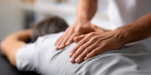 Person receiving gentle spinal therapy in a bright clinical room beside an exercise mat and treatment table